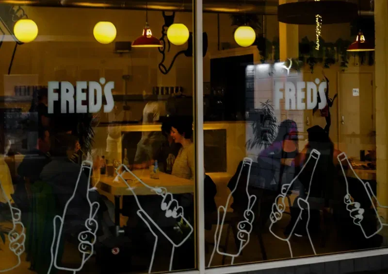 Fred's windows at night with hand-drawn beer bottles